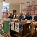 un tavolo con alcuni relatori e manifesti appesi