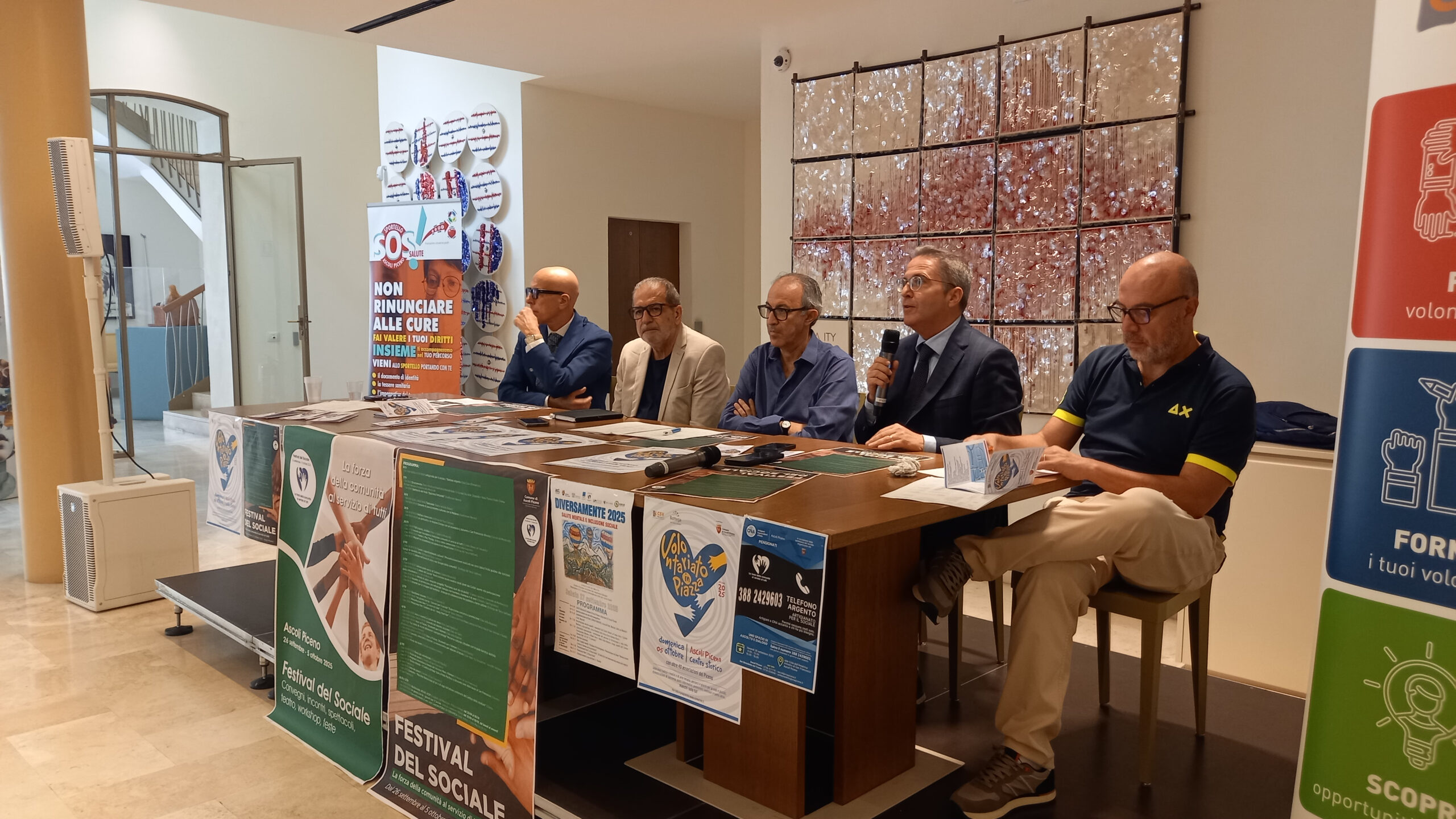 un tavolo con alcuni relatori e manifesti appesi