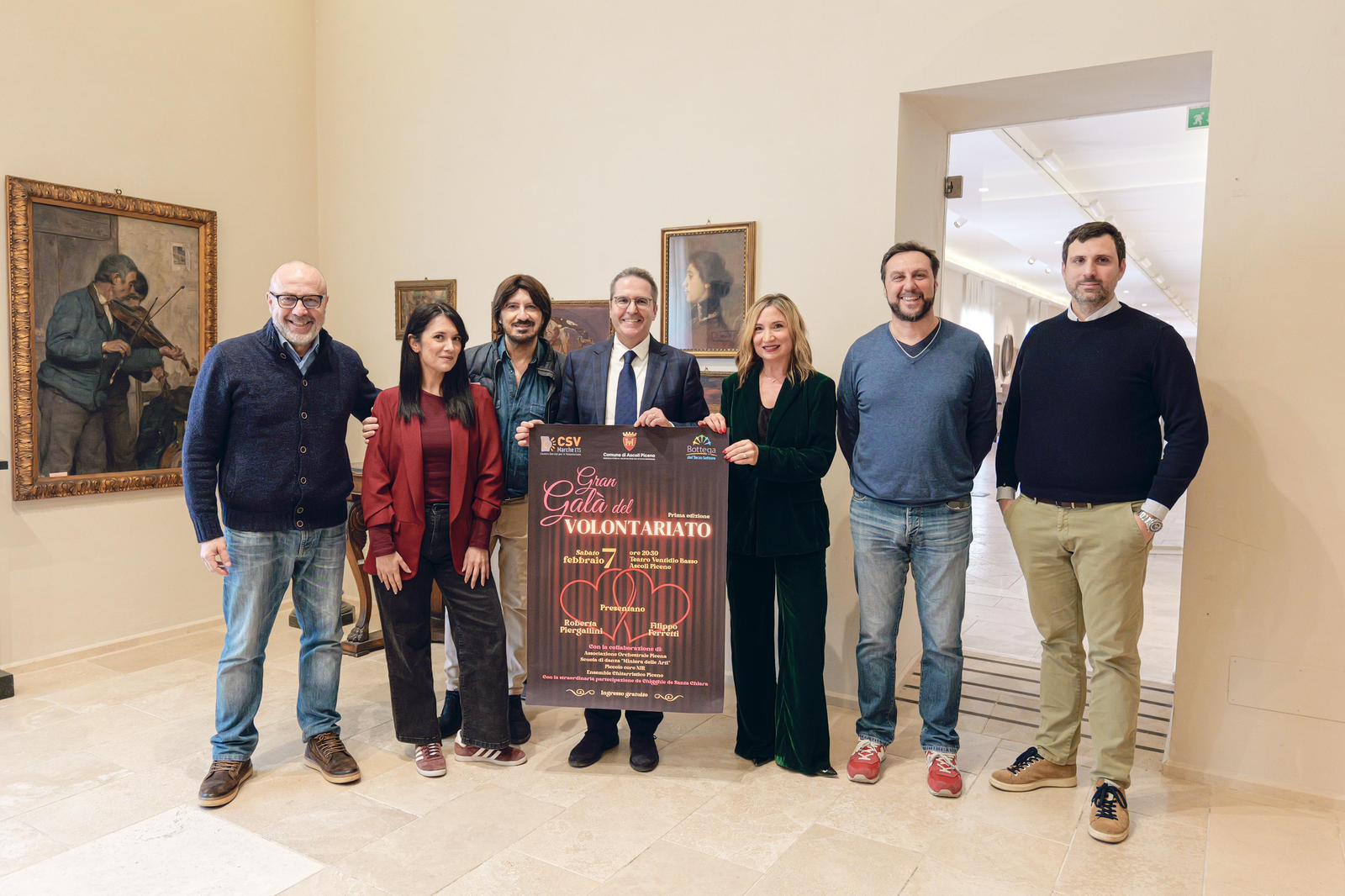 il gruppo degli organizzatori in piedi con il manifesto dell'evento