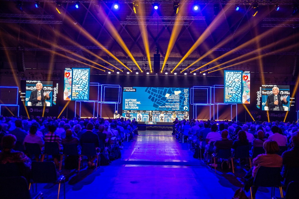 un auditorium gremito di pubblico e in fondo un palco con relatori