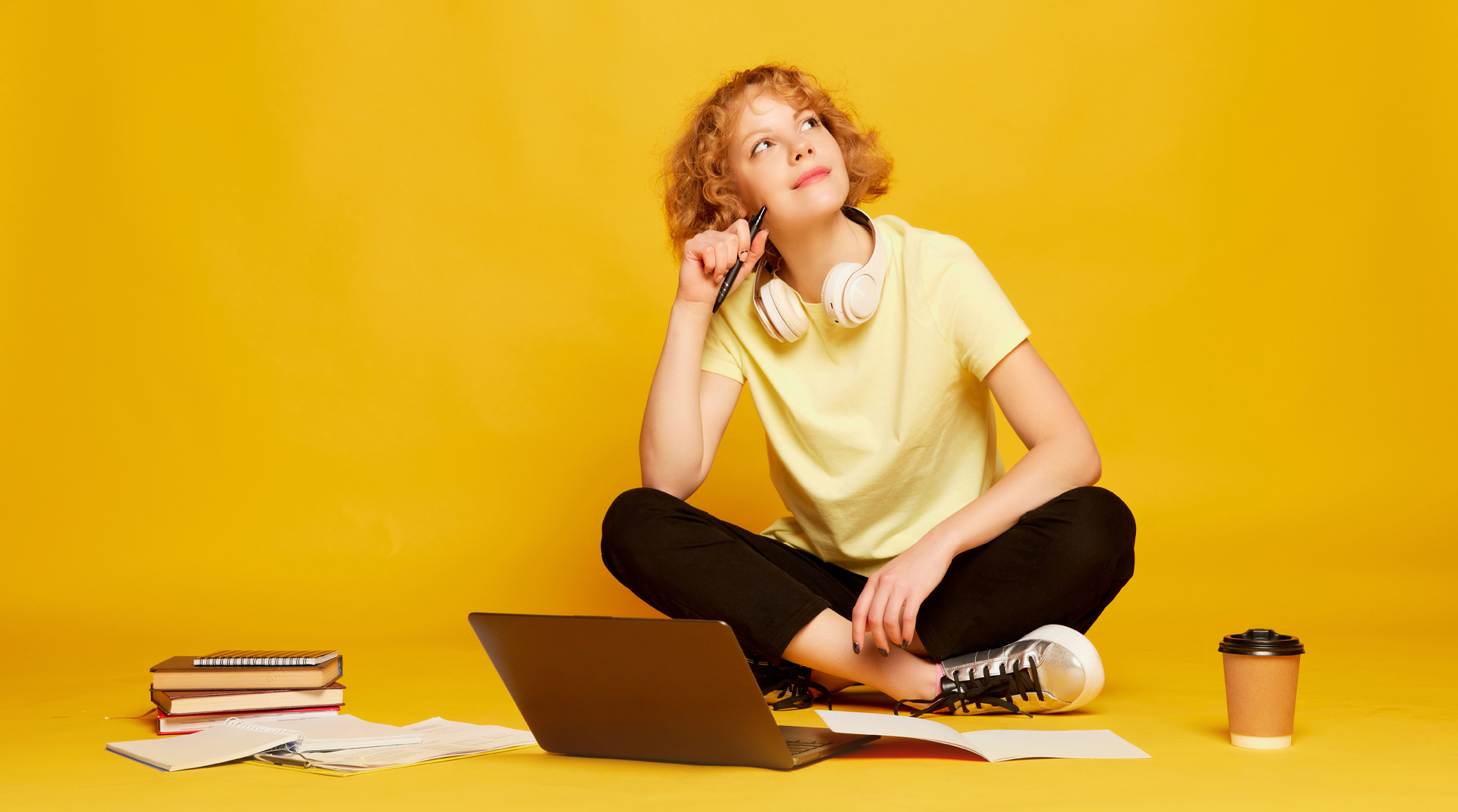 ragazza seduta davanti a un pc studia e pensa con aria sognante