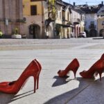 alcune paia di scarpe rosse da donna disposte su una piazza a simboleggiare il contrasto alla violenza di genere