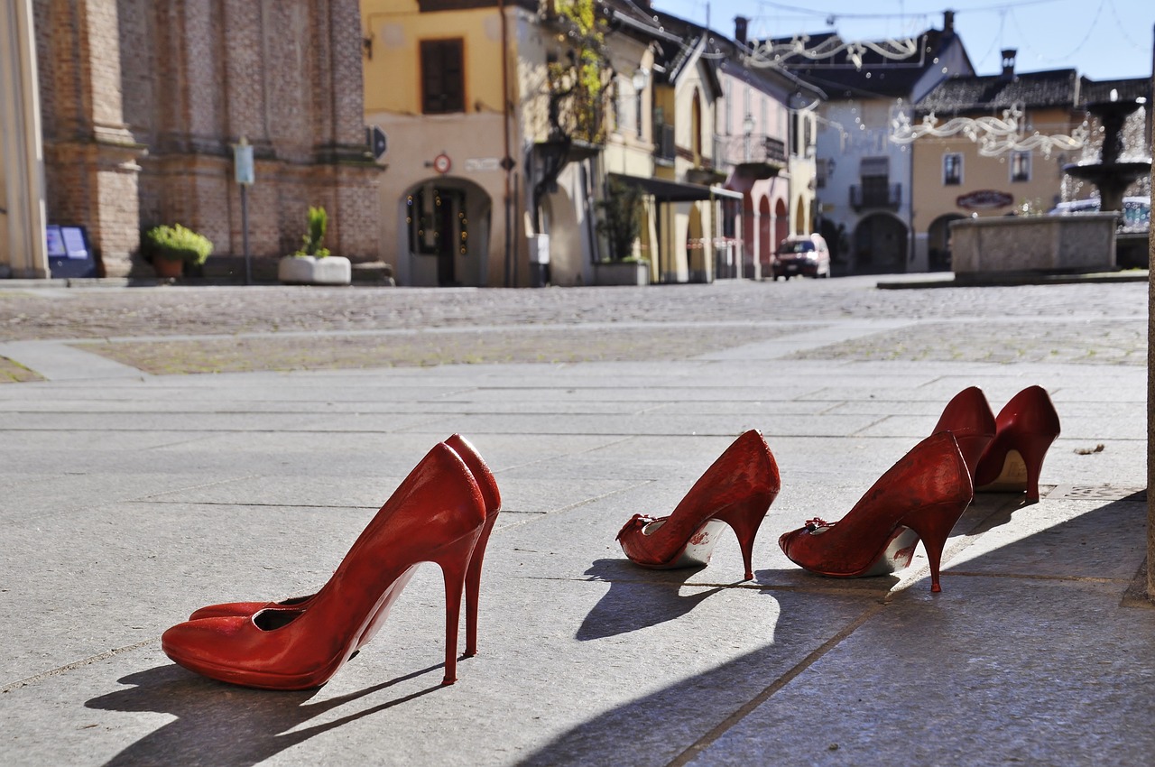 alcune paia di scarpe rosse da donna disposte su una piazza a simboleggiare il contrasto alla violenza di genere