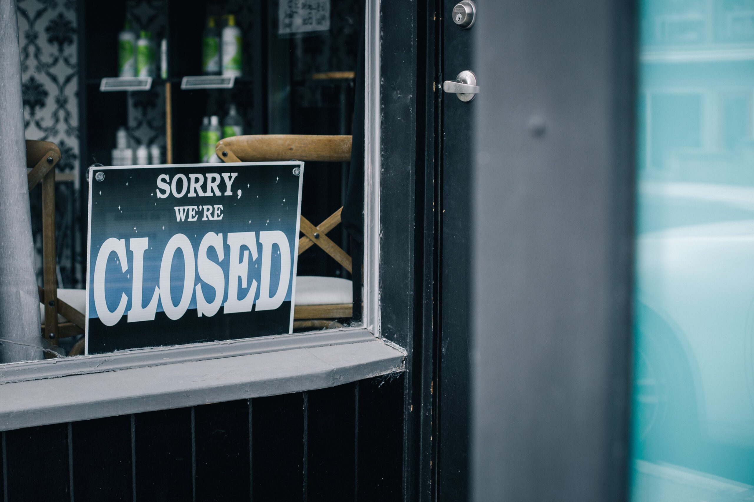 un cartello con la scritta "Sorry we're closed" dietro una porta a vetri